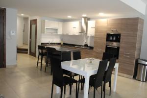 cocina con mesa blanca y sillas negras en Hal Saghtrija E7, en Żebbuġ