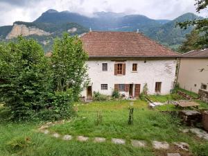 an old white house with mountains in the background at Deux appartements - Gîte aux 1000 chemins in Saint-Joseph-de-Rivière