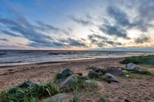 a sandy beach with rocks and the ocean at Sunlay Cottage in Zvejniekciems