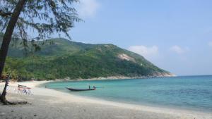 a boat sitting on a beach next to the ocean at Bottle Beach 2 Bungalows in Bottle Beach