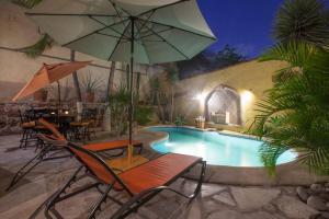 a swimming pool with chairs and an umbrella at 20 ft to malecón, downtown, private Pool in La Paz