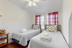 ein Schlafzimmer mit zwei Betten und einem Deckenventilator in der Unterkunft Hen Cove Cottage in Pocasset