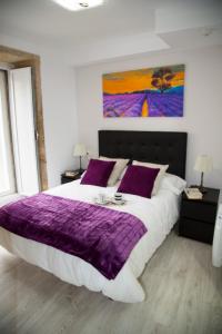 Un dormitorio con una cama grande con mantas y almohadas púrpuras. en Xavestre Rooms Santiago, en Santiago de Compostela