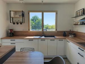 a kitchen with white cabinets and a sink and a window at Maison 3 chambres avec jardin calme et Nature in Nontron