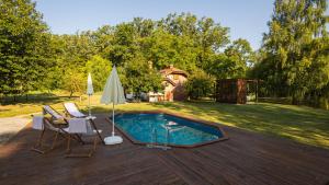 a swimming pool with two chairs and an umbrella on a deck at Rudine 41 - Off-Grid Riverside Home in Rokovci