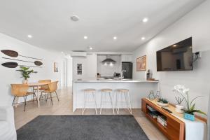 a kitchen and living room with a counter and stools at Paihia Waterfront Apartment 2 Bedroom with Pool in Paihia