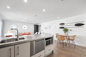 a kitchen with a sink and a table with chairs at Paihia Waterfront Apartment 2 Bedroom with Pool in Paihia