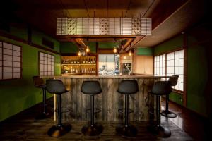 a bar with black stools in a green kitchen at Backpacker's House Kamome in Fujiyoshida