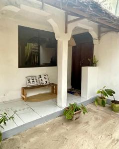 un porche de una casa con una mesa y algunas plantas en Palm & Earth Rooms, en Jambiani