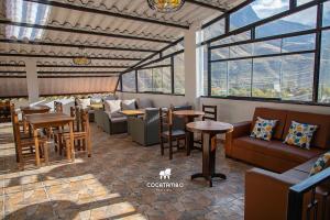 a restaurant with couches and tables and windows at Cocatambo in Ollantaytambo