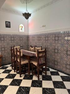 ein Esszimmer mit einem Tisch und einem karierten Boden in der Unterkunft Riad Tamounte piscine palmeraie in Marrakesch