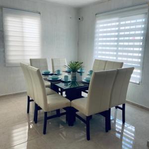 a dining room table with white chairs and a black table at Casa venue in Mérida +3 photos