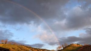 a rainbow in a cloudy sky with trees and houses at Sudoeste Guest House in Odeceixe