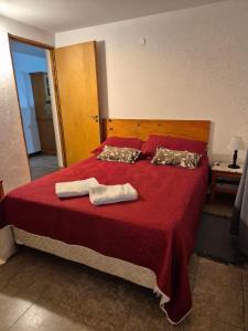 a bedroom with a red bed with two towels on it at Departamento E.M.A in Esquel