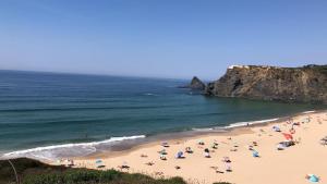 a group of people on a beach with umbrellas at Sudoeste Guest House in Odeceixe
