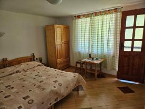 a bedroom with a bed and a table and a window at Къщи за гости Кедър in Varna City