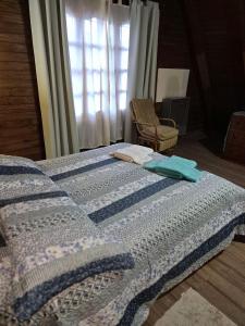 1 dormitorio con 1 cama con manta y silla en Freecis, en Esquel