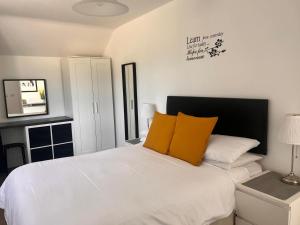 a bedroom with a white bed with two yellow pillows at Footpath Cottages  +46 photos