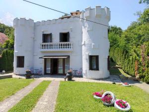 a white house with some flowers in the yard at Dvorac Castelo DB 2022 in Vrnjačka Banja