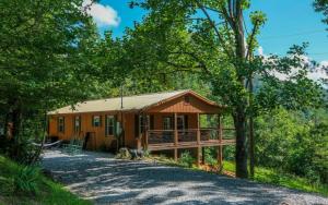 a cabin in the woods with a driveway at Cozy Bear Camp in Sevierville