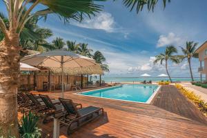 a pool with chairs and an umbrella next to the ocean at Moana Sands Lagoon Resort - Adults Only in Rarotonga