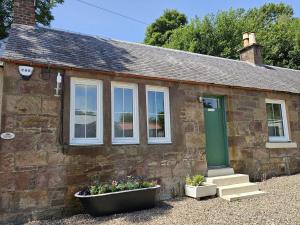 a stone house with a green door and two windows at Wee Lyon Cottage Maybole 2 Bedroom Sleeps 4 in Maybole