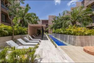 a row of chaise lounge chairs next to a swimming pool at Homu Apartments in Mérida