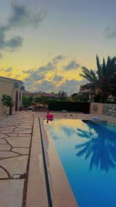 a swimming pool with a sunset in the background at قريه المروه الساحل الشمالي فيلا 5 غرف وحمام سباحه خاص in Dawwār ‘Abd Allāh