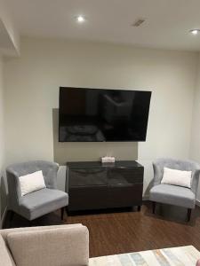 Una sala de estar con dos sillas y un televisor de pantalla plana. en Cozy and modern Pemberton Heights Suite, en North Vancouver