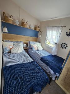 威尔汉姆Jurassic Bliss - stylish static caravan with partial sea view at Durdle Door的配有两张蓝色和白色床单的床铺