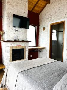蒙特韦尔迪Vila Ninho da Maritaca的带一张大床和一个壁炉的卧室
