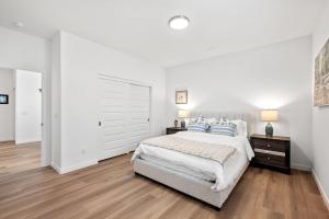 a white bedroom with a large bed with blue pillows at Spacious 5BR Getaway w Game Room & Modern Comfort in Fontana