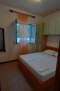 a bedroom with a white bed and a window at Apartments by the sea Drace, Peljesac - 24429 in Drače