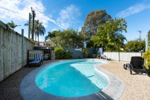 a swimming pool in a backyard with chairs and a fence at Noosa River Sandy Shores in Noosaville