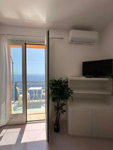 a living room with a television and a balcony at Praiano Amalfi Coast Casa con Vista Mare in Praiano