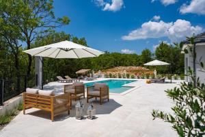 a patio with chairs and an umbrella next to a swimming pool at NEW! Villa Angela A modern Family Retreat in Krivodol