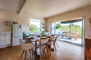 Waiheke IslandにあるBeachlovers Onetangi - Stay Waihekeのテーブルと椅子のあるキッチンとダイニングルーム