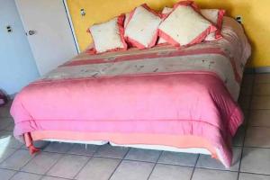 a pink bed with pillows on it in a room at Casa Mandarina in Tequesquitengo