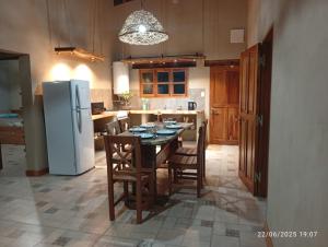 a kitchen with a table with chairs and a refrigerator at Cabañas El Alemán 2 in Cerrillos +6 photos