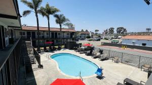 a swimming pool with chairs and umbrellas on a building at Studio 6 Suites San Ysidro CA San Diego South Bay in San Ysidro