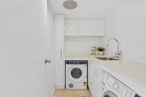 a white kitchen with a washing machine and a sink at Sun-Kissed Escape - Broadbeach Gem - Hosted by Coastal Letting Co. in Gold Coast +11 photos