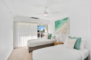 two beds in a white room with a window at Sun-Kissed Escape - Broadbeach Gem - Hosted by Coastal Letting Co. in Gold Coast