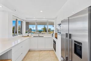 a kitchen with white cabinets and a stainless steel refrigerator at Sun-Kissed Escape - Broadbeach Gem - Hosted by Coastal Letting Co. in Gold Coast