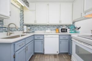a white kitchen with blue cabinets and a sink at Harbor House B19 condo in Gulf Shores