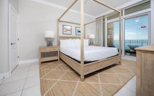 a bedroom with a canopy bed and a balcony at Phoenix Orange Beach II 1702 condo in Orange Beach