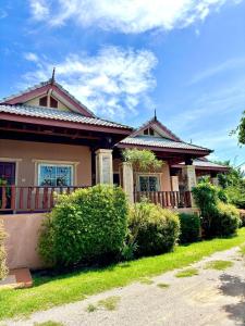 una casa con arbustos delante de ella en เฮือนฮิมน้ำ รีสอร์ท, 