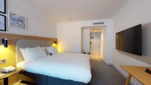 a hotel room with a bed and a flat screen tv at Holiday Inn Cambridge by IHG in Cambridge