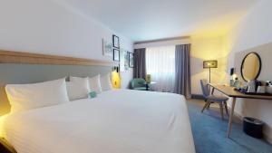 a hotel room with a large white bed and a desk at Holiday Inn Cambridge by IHG in Cambridge