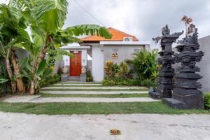 a white house with a red door and some plants at Villa Uma Tegal Cemagi in Cemagi