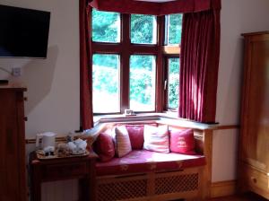 a couch sitting under a window with red curtains at Gardeners Cottage B and B in Bakewell